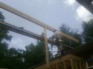 Carpenter setting a ridge beam over a new addition frame — Ice Dam Removal by Roofing Brothers in Dellrose