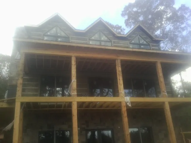 Dormers and porch framing on a large log home under construction — Roof Coating work by our crew in Dellrose