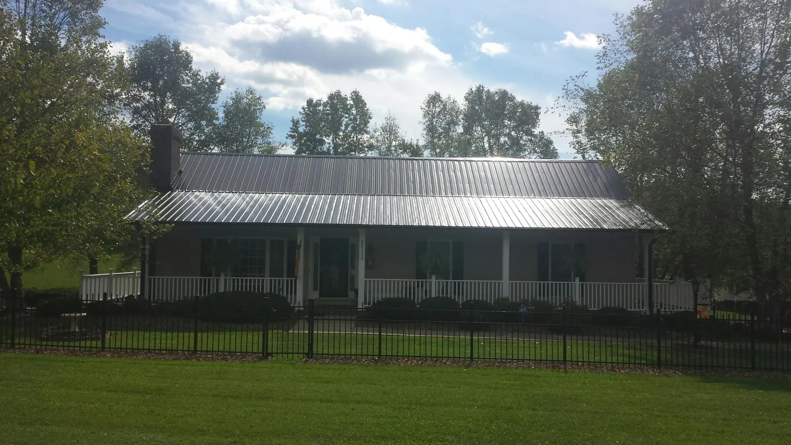 Gray metal roof on a brick ranch with a full width front porch — Gutter Guard Installation work by our crew in Dellrose