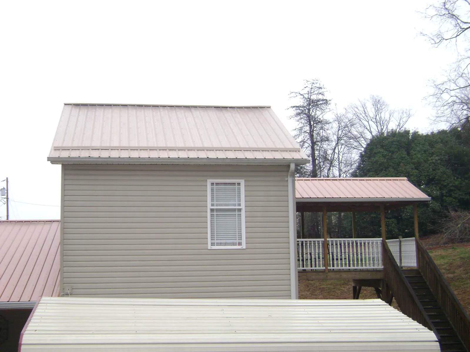 Tan metal roofs on a two story addition and attached porch, from a Roof Replacement job in Dellrose
