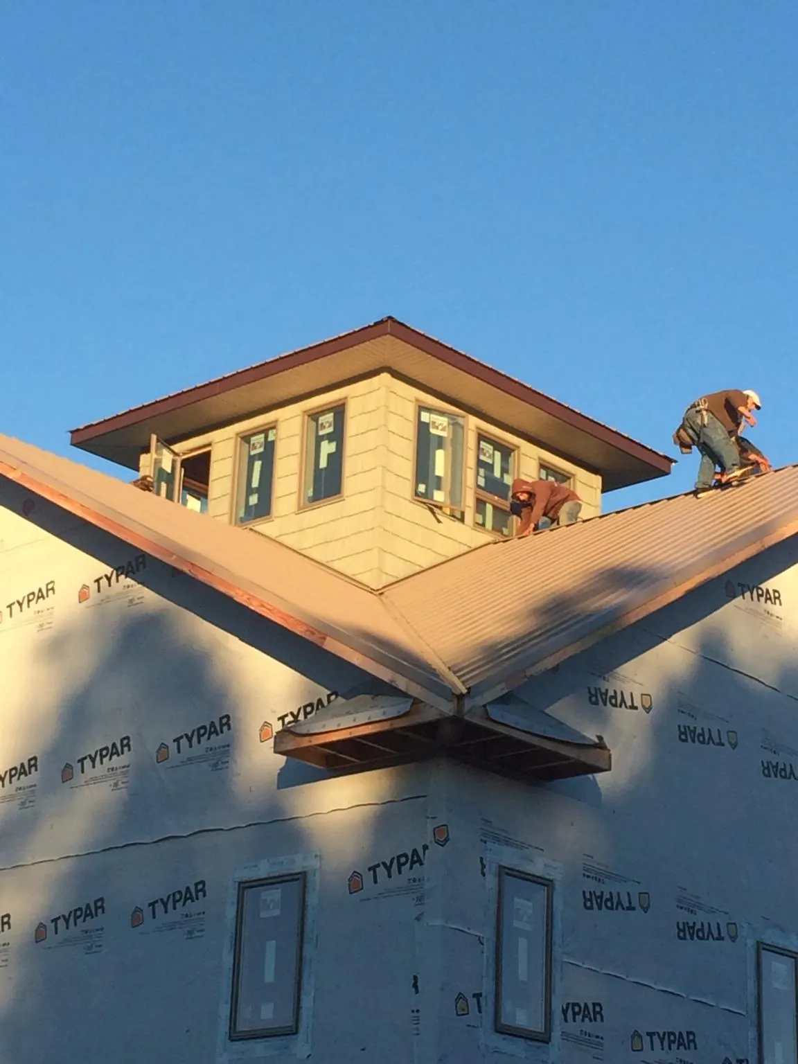 Roofers working around a rooftop cupola on a new metal roof at sunset — Roof Waterproofing in Dellrose by Roofing Brothers